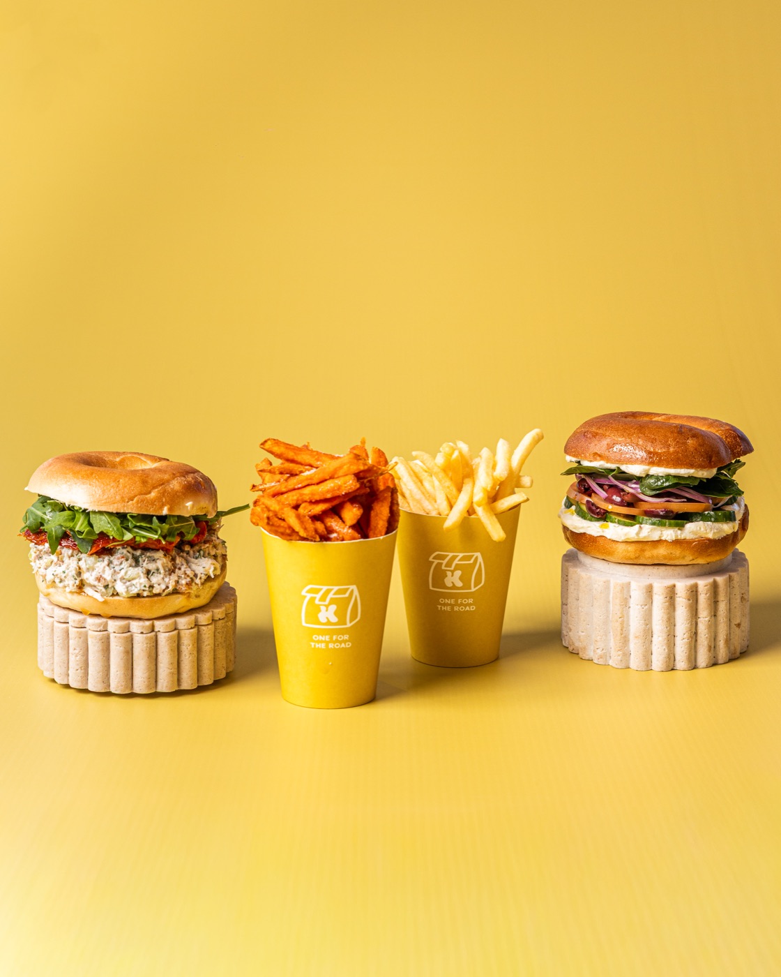 Two burgers with cups of golden chips