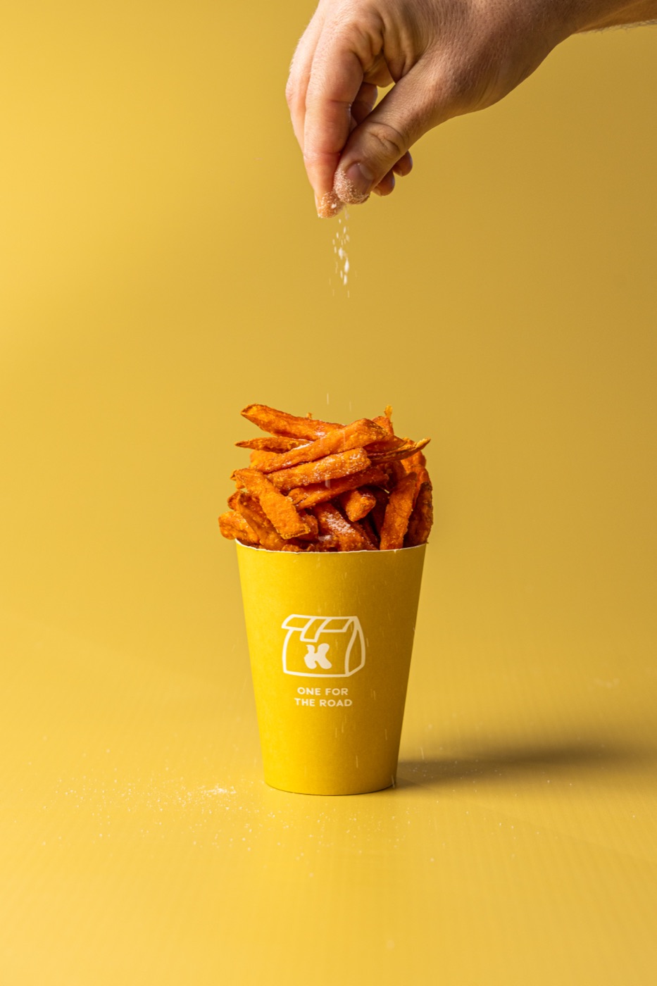 Sweet potato fries in a Kanteen cup with salt being sprinkled on top